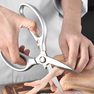 ciseaux-de-cuisine-personne-qui-coupe-une-patte-de-poulet