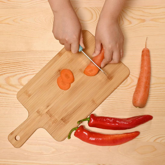 planche-a-decouper-personne-qui-coupe-des-carotte-et-piment